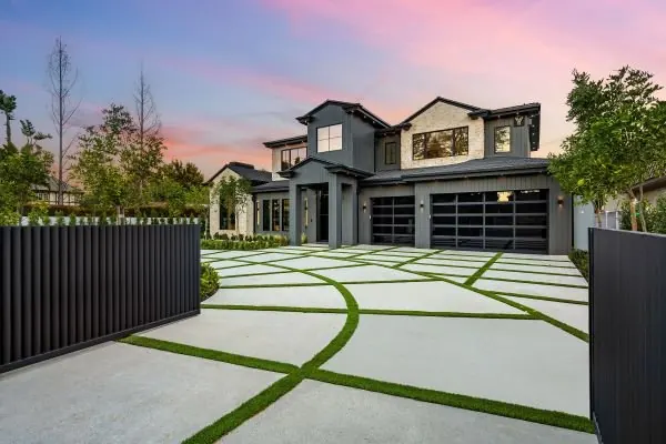 Exposed concrete driveway panels separated by lawn joints in front of a new home